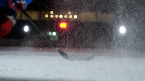 Close-up-slow-motion-hockey-puck-and-flying-snow-on-the-ice-,-hockey-player-picks-up-the-puck-stick